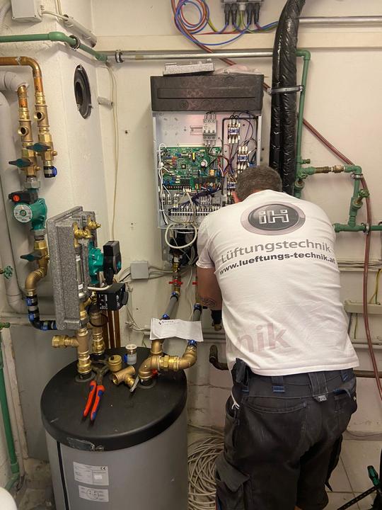 Monteur schließt die Hydraulik der Wärmepumpe am Speicher an